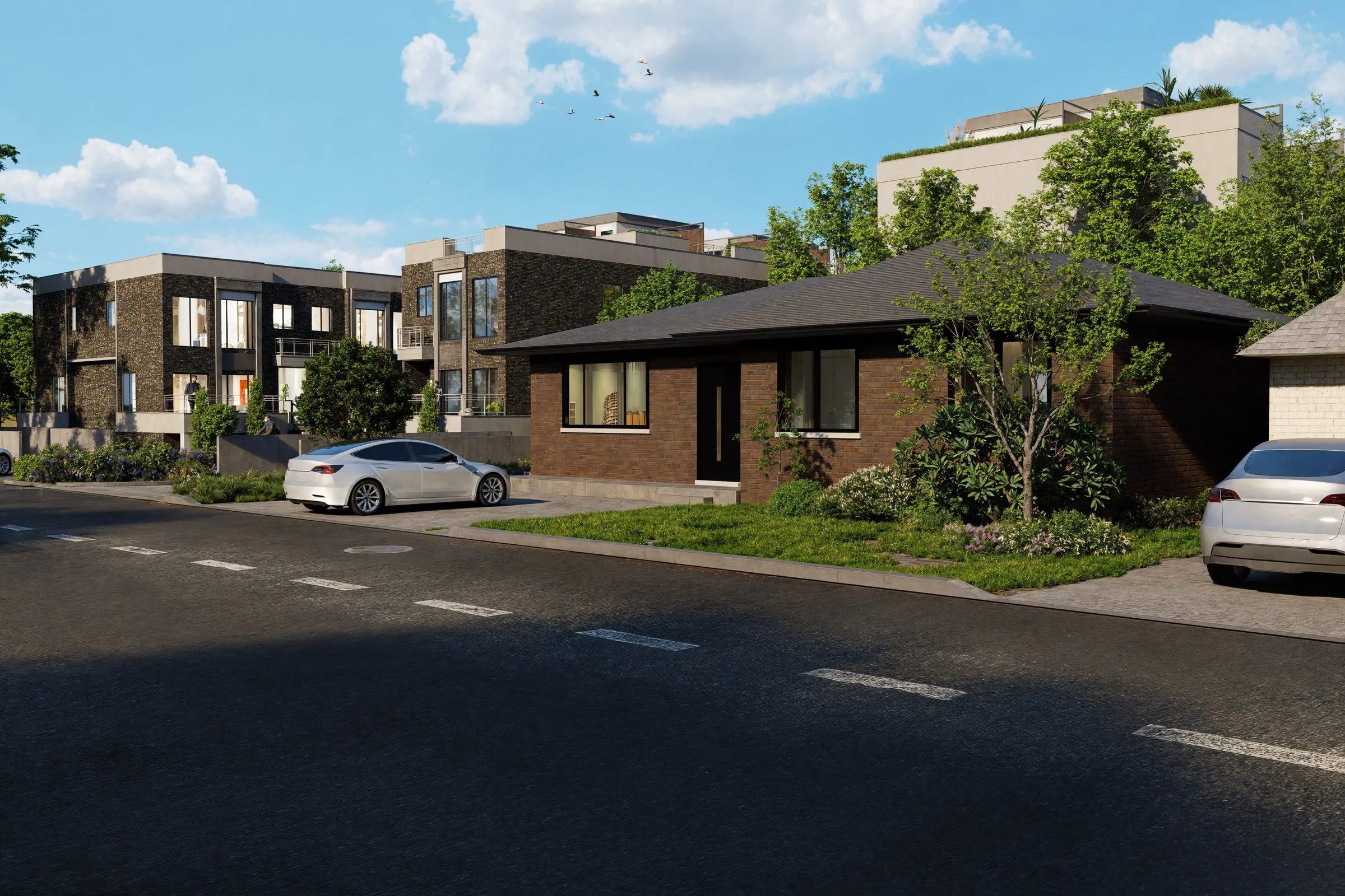 Street-level view of dark stone-clad townhouses with lit windows beside an existing brick bungalow, with parked cars and a clear afternoon sky